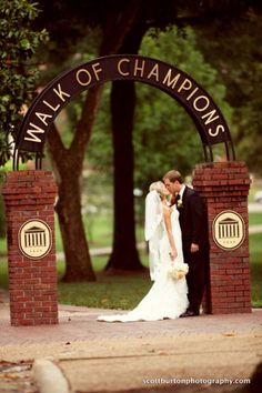 a bride and groom kissing in front of the walk of champions sign at their wedding