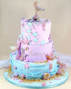 there is a three layer cake with mermaid decorations on it