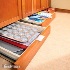 an open drawer in the middle of a kitchen with muffin pans on it