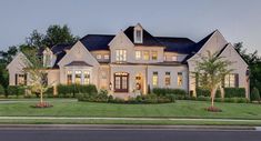 a large white house sitting on the side of a road next to a lush green field