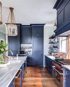 a large kitchen with blue cabinets and wood flooring, along with white counter tops