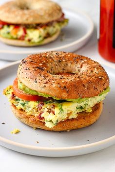 a bagel sandwich on a plate next to a bottle of juice