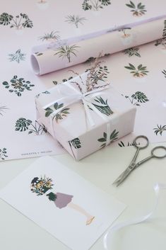 wrapping paper and scissors are on the table next to a gift wrapped in floral designs