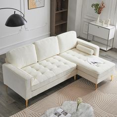 a white sectional couch sitting on top of a rug in a living room next to a coffee table