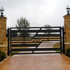 a gated entrance to a home with stone pillars