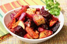 a white bowl filled with cooked vegetables on top of a colorful table cloth next to a fork