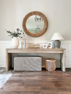 a table with a mirror, lamp and vase on it in front of a white wall