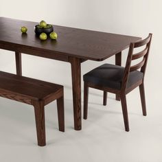 a wooden table with two chairs next to it and some fruit on top of the table