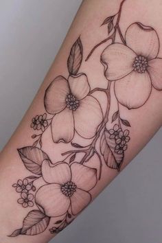 a flower tattoo on the arm with leaves and flowers around it's center piece