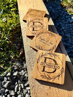 three wooden coasters sitting on top of a wooden bench next to grass and rocks