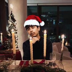 a man wearing a santa hat sitting at a table with candles in front of him