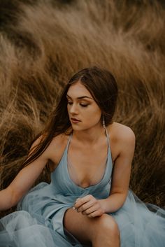 a woman in a blue dress sitting on the ground