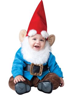 a baby wearing a santa hat and sitting on the ground with his hands in his pockets