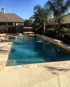 a swimming pool surrounded by palm trees and other tropical plants in a backyard area with stone steps leading up to it