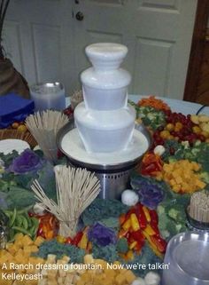 a table topped with lots of different types of food next to a white vase filled with flowers