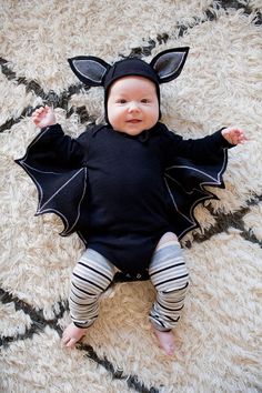 a baby wearing a bat costume laying on a rug