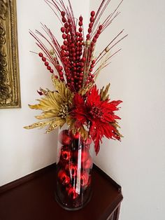 a vase filled with red flowers on top of a wooden table