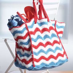 a red, white and blue crocheted bag sitting on top of a chair