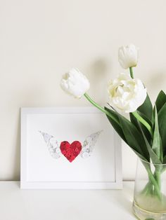 white tulips are in a vase next to a card with an angel's wing on it