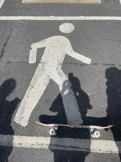 a skateboarder is walking across the street in front of a pedestrian crossing sign