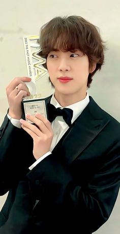 a young man in a tuxedo holding an award