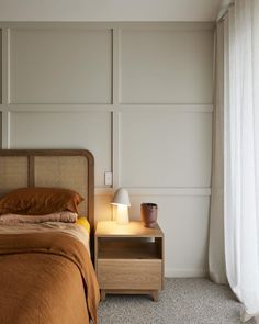 a bed sitting next to a night stand with a lamp on it's side