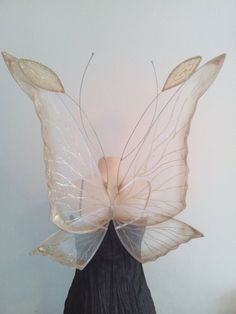 a woman's head wearing a white butterfly wings and black dress with gold accents