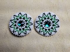 two green and white beaded buttons sitting on top of a carpet