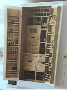 an open cabinet with lots of drawers and bottles in it's doors, sitting on top of a white countertop