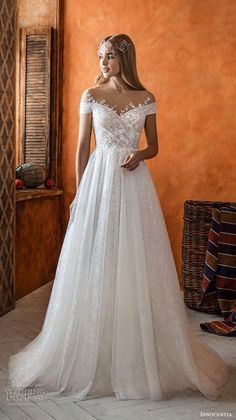 a woman in a white wedding dress standing next to an orange wall and wearing a tiara