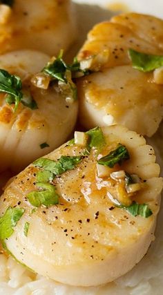 some scallops are sitting on top of rice and garnished with herbs