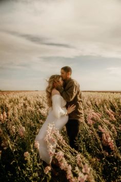 a bride and groom kissing in a field of flowers