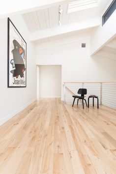 an empty room with two chairs and a poster hanging on the wall above it's stairs