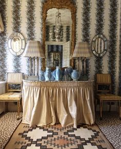 a living room with two lamps and a table in front of a mirror on the wall