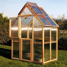 a small wooden greenhouse sitting in the grass