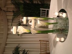 flowers and candles are arranged in glass vases on a table