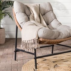 a chair with a blanket on top of it next to a potted plant and rug