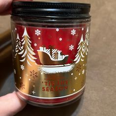 a hand holding a jar with a christmas scene on it