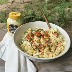 a white bowl filled with pasta and shrimp next to a jar of garlic breadcrumbs