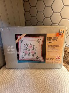 the cross stitch pillow is in its box