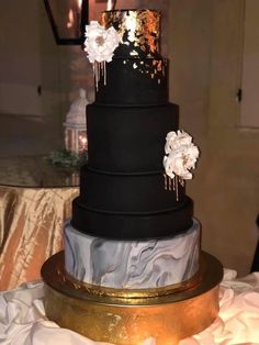 a black and gold wedding cake with white flowers