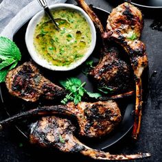 grilled lamb chops with pesto sauce and mint garnish on a black plate