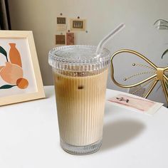 a glass with a straw in it sitting on a table next to a framed photograph