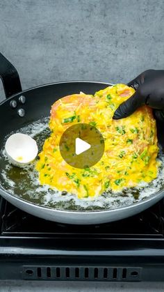 someone in black gloves is frying omelet on a stove top with an egg