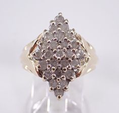 a diamond cluster ring is displayed on a clear stand