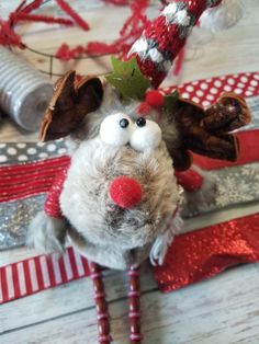 a stuffed animal with a red nose and antlers on it's head sitting next to ribbon