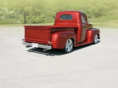 an old red truck parked in a parking lot