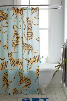 a bathroom with a shower curtain that has tigers on it and blue letters in the floor