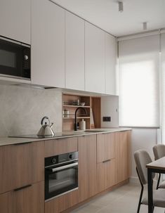 a kitchen with a stove, microwave and dining room table in the backround