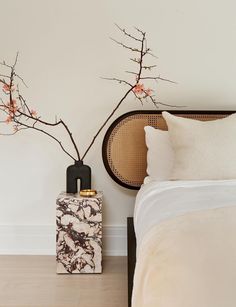 a bedroom with a bed, nightstand and vase on the floor